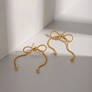 Detail of gold bow earrings with tassels showing high-gloss metallic finish and elegant shine