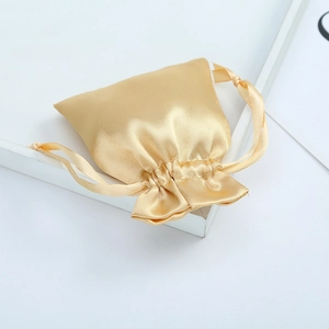 Golden satin drawstring jewelry pouch with smooth silk texture for elegant gift packaging