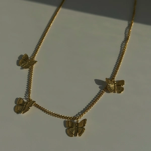 Detailed macro view of retro butterfly charms on a gold titanium steel necklace chain