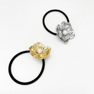 Detail of elegant black elastic hair ties featuring gold and silver flowers with pearls