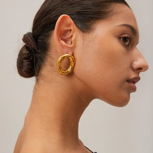 Detail shot of a model wearing chunky 18k gold plated stainless steel oval hoop earrings