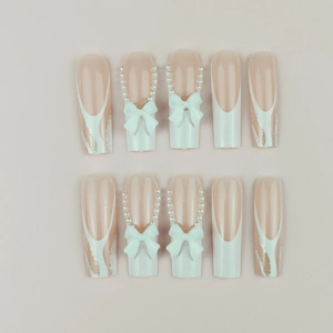 Long coffin french nails with white bows, pearls, and silver glitter lines on pink base