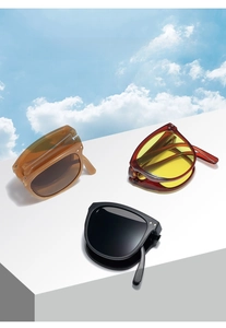 Portable folding square sunglasses in amber, red and black frames on a geometric stand