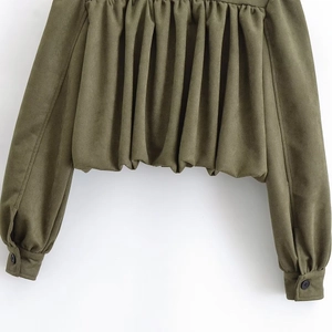 Macro detail of olive green suede jacket featuring pleated hem and buttoned cuffs