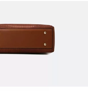 Macro detail of brown leather bag bottom with crocodile texture and gold metal studs