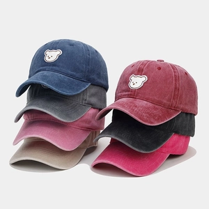 Close-up showing various colors of washed cotton baseball caps with bear embroidery