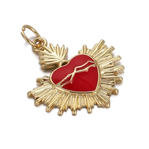 Detail of a golden heart pendant with red enamel inlay and radiant sunburst design