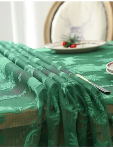 Close-up of green Christmas lace tablecloth featuring reindeer and pine tree woven patterns