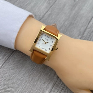 Classic square gold women's watch with white dial and brown leather strap on wrist