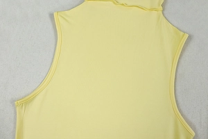 Detailed close-up of yellow sleeveless dress neckline with elastic knit texture
