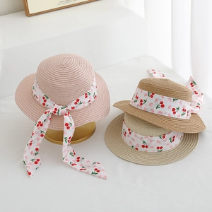 Kids flat top straw sun hats with red cherry print ribbons and bows for summer beach trips