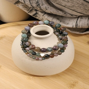 Three-piece vintage natural stone beaded bracelets with heart pendant on wood tray