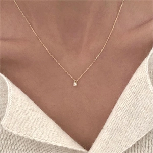 Close-up of minimalist gold O-chain necklace with a single round zircon on a model