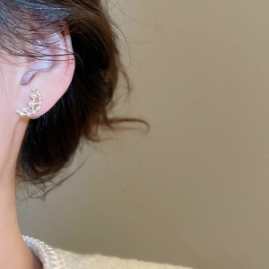 Close-up detail of moon shaped gold plated earrings with pearls on model's ear