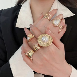 Detailed macro view of vintage gold rings with irregular lava texture and pearl inlay