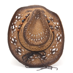 Brown woven straw cowboy hat with hollow patterns and bead decor on white background