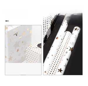 Detail view of white gift wrapping paper with gold foil star and geometric patterns