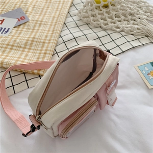 Detail view of pink and white canvas crossbody bag showing open main pocket and front buckle