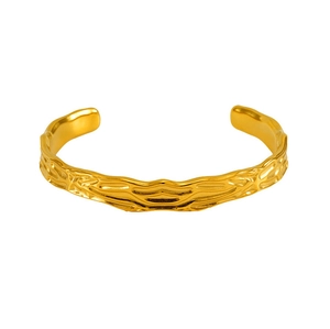 Detail of golden adjustable open bangle featuring a modern irregular hammered metal texture