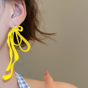 Close-up of bright yellow wavy ribbon earrings with sparkling rhinestone accent on ear