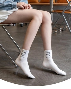 Detail of white cotton crew socks featuring a cute black bear print and HAPPY DAY text