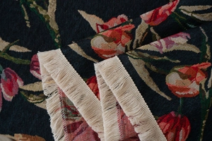 Detailed view of jacquard floral weave with deep blue tones and creamy white fringe