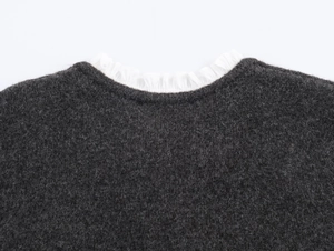 Close-up of dark grey knit sweater featuring a white poplin ruffled collar detail