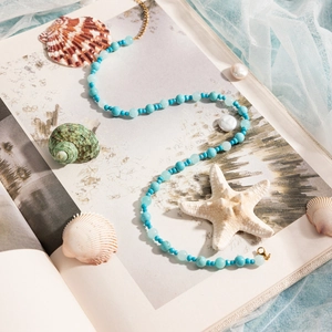 Detailed shot of turquoise beaded necklace on a book with starfish and seashells