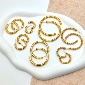 Close-up of gold hoop earrings set with polished and twisted textures in a tray