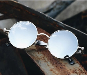 Detail of silver steampunk sunglasses with reflective lenses on industrial metal beam