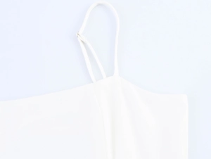 Detail view of adjustable thin shoulder straps on white tropical vacation style dress