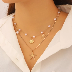 Dettagli della collana dorata a strati con perle e ciondoli a forma di stella marina