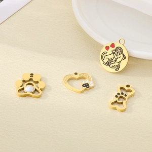Macro view of four 18k gold pet themed charms including paw prints and bone shapes