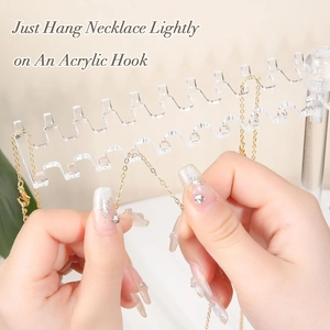Detail showing hands hanging a gold necklace on a clear acrylic organizer hook