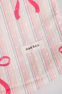Close-up of pink and blue striped cotton makeup bag with dotted jacquard and brand label