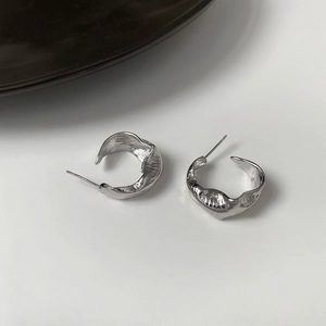 Minimalist silver geometric C-shape earrings with irregular lava texture and liquid metal finish