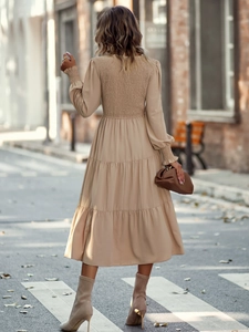 Détail du dos smocké et de la jupe plissée à plusieurs niveaux sur la robe beige