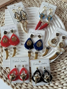 Vista detallada de varios pendientes retro con cabeza de toro y colmillo en múltiples colores