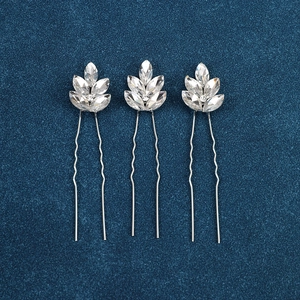 Detailed view of three silver U-shaped hair pins with marquise crystal leaf designs