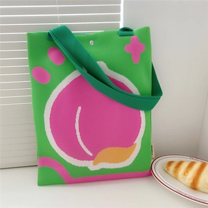 Detail of green knitted tote bag with peach pattern and secure metal snap closure