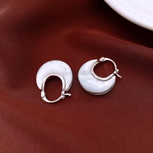 Detail of U-shaped earrings with white mother-of-pearl texture on vintage velvet