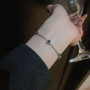 Detailed view of silver bow bracelet with emerald green stones and sparkling pavé crystals