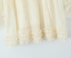 Gros plan d'une robe crème à volants avec des détails de broderie et de texture
