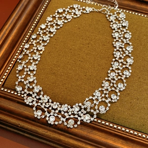 Detail of silver lace necklace featuring sparkling rhinestones on a vintage velvet background