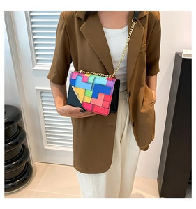 Detail of colorful geometric puzzle pattern shoulder bag with golden chain strap