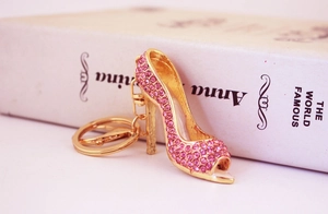 Detail of pink crystal high heel keychain with gold plating and lobster clasp on a book
