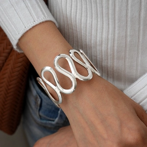 Close-up of a silver wavy cuff bracelet on a female wrist for a minimalist style look