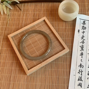 Detail view of translucent brownish glass bangle on a wooden tray with Zen decor