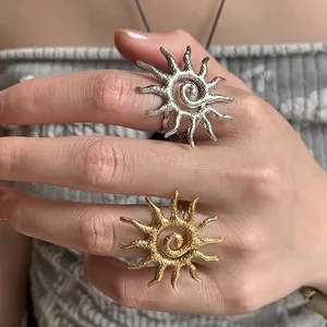 Exaggerated sun-shaped open rings in gold and silver finish with hammered metal texture
