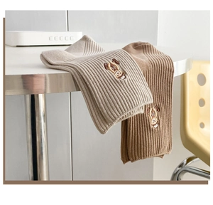 Détail de chaussettes en coton côtelé avec broderie ours aux tons terreux